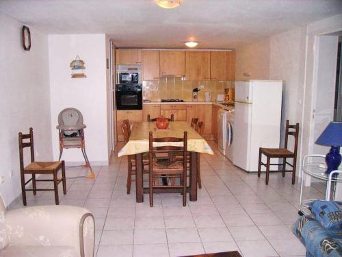 a kitchen with a table and chairs and a refrigerator at Appartement charmant à Breuillet avec jardin spacieux in Breuillet