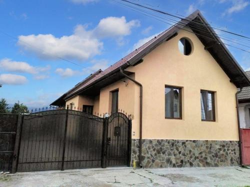a house with a black gate and a fence at Charming House in Săcele with Garden View + BBQ in Săcele