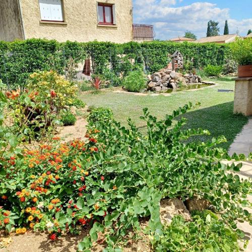 a garden with a bunch of flowers in front of a house at Appartement charmant à Vias + jardin in Vias