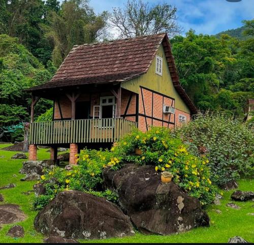 a small house with a deck and flowers in the yard at Paraíso Enxaimel Mundo Antigo in Pomerode