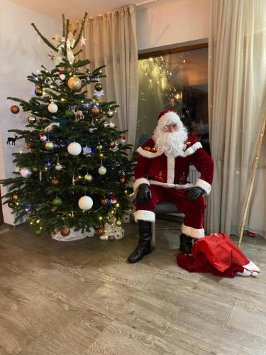 a santa claus sitting next to a christmas tree at Mountain View PM in Poiana Mărului