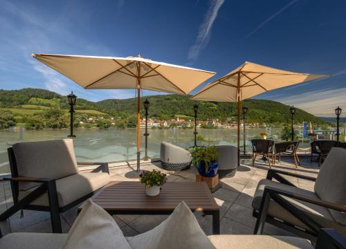 a patio with chairs and tables and umbrellas at Romantikhotel Residenz Wachau in Aggsbach Dorf