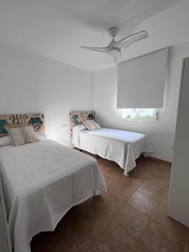 Un dormitorio con dos camas y un ventilador de techo. en Casa Turquesa, en San José