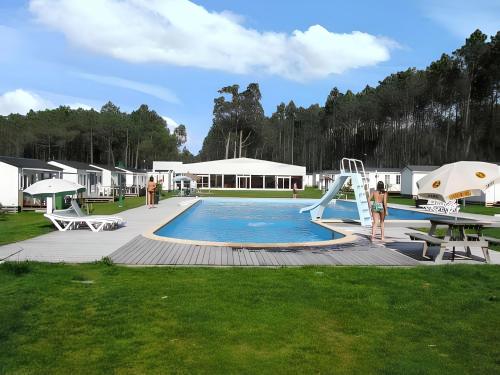 a pool with a slide and people standing around it at Comfortable Bungalow Near Pataias with Shared Pool in Pataias