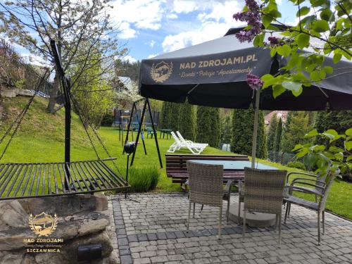 a patio with a swing and a table and chairs at "Nad Zdrojami" Domek Kowalczyk in Szczawnica