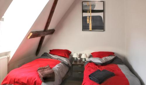 エギスハイムにあるAppartement cosy avec cheminée à Eguisheim - 110m² - Terrasseの屋根裏のベッドルーム(赤い枕付)のベッド2台