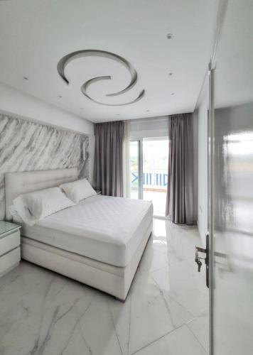 a white bedroom with a bed and a large window at Bright apartment in Marina Smir, sea view and shared pool in Marina Smir