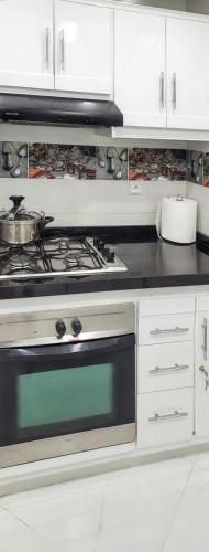 a kitchen with a stove and white cabinets at Bright apartment in Marina Smir, sea view and shared pool in Marina Smir