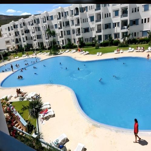 a large swimming pool in front of a large apartment building at Bright apartment in Marina Smir, sea view and shared pool in Marina Smir