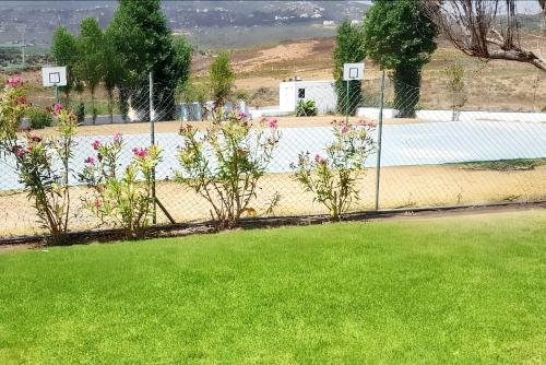 a fence with a yard with green grass and flowers at Bright apartment in Marina Smir, sea view and shared pool in Marina Smir