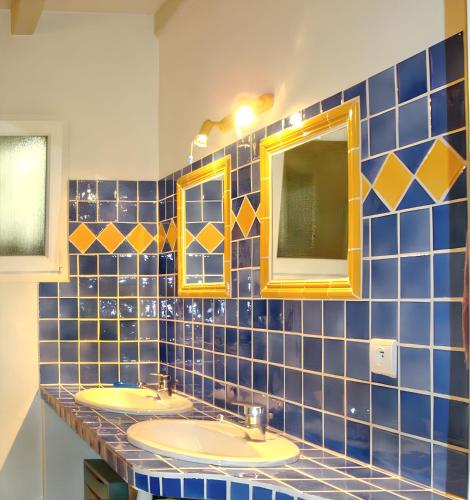 - une salle de bains carrelée de bleu avec trois lavabos et deux miroirs dans l'établissement Villa charmante à Dauphin avec piscine privée, à Dauphin
