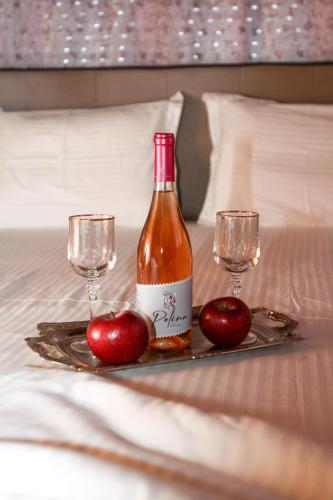 a bottle of wine and two glasses on a bed at VILA SOFi in Néa Karyá