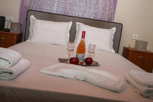 a bed with a bottle of wine and two glasses at VILA SOFi in Néa Karyá