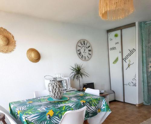 une salle à manger avec une table et une horloge au mur dans l'établissement Studio cosy à Saint-Cyprien, vue mer, 22 m², à Saint-Cyprien