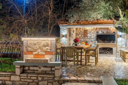 a stone patio with a table and chairs and a fireplace at Villa Aurora in Grizáta