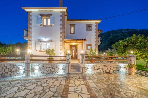 a large white house with a stone walkway at Villa Aurora in Grizáta