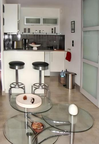une cuisine avec deux tabourets et une table en verre dans l'établissement Studio charmant à Villers-sur-Mer avec terrasse - 33 m², à Villers-sur-Mer
