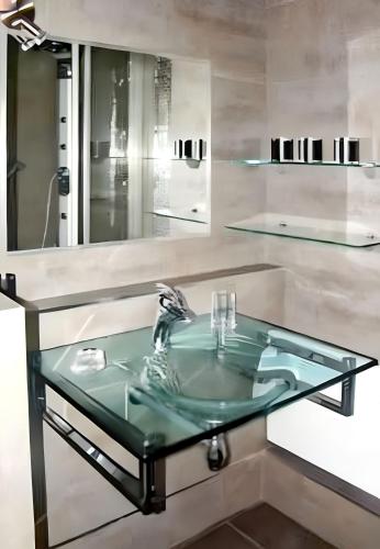 La salle de bains est pourvue d'un lavabo en verre et d'un miroir. dans l'établissement Studio charmant à Villers-sur-Mer avec terrasse - 33 m², à Villers-sur-Mer