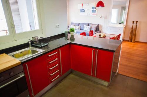 a kitchen with red cabinets and a sink and a living room at Apartamento Alameda in Valencia