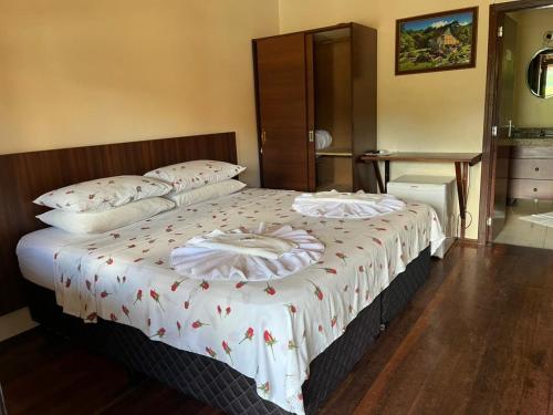 a bedroom with two beds with white blankets and pillows at Paraíso Enxaimel Mundo Antigo in Pomerode