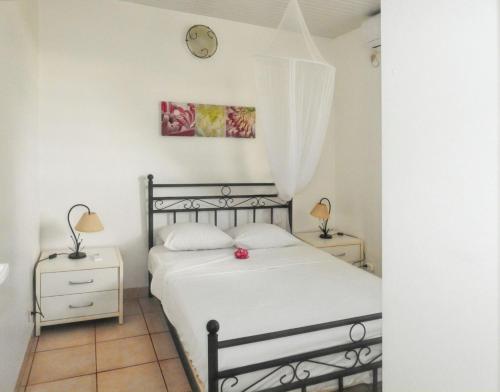 una camera da letto con un letto e un orologio a parete di Bungalow charmant au Robert + piscine a Le Robert