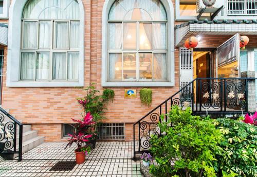 a brick house with windows and plants in front of it at Flower Bird House B&B in Jiaoxi