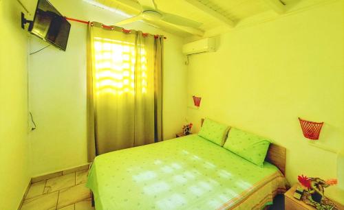 a small bedroom with a green bed and a window at Charmante Maison à Capesterre-Belle-Eau avec Jardin et Terrasse in Capesterre-Belle-Eau