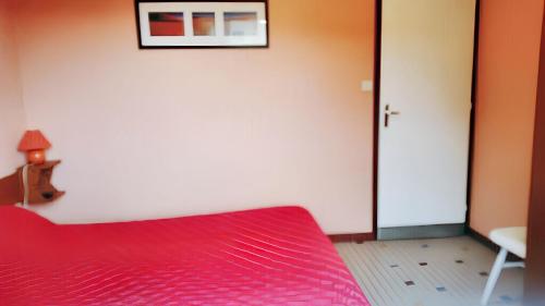 - une chambre avec un lit rouge et un mur blanc dans l'établissement Appartement charmant à Mimizan, 25 m², proche plage, à Mimizan