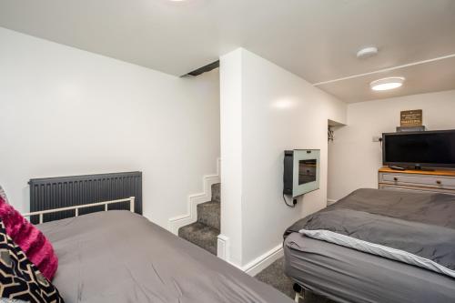 a bedroom with a bed and a flat screen tv at The Tucked-away Cottage in Huddersfield