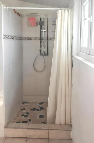 a bathroom with a shower with a shower curtain at Maison de charme à Saint-Pierre avec vue sur mer et montagne in Saint-Pierre