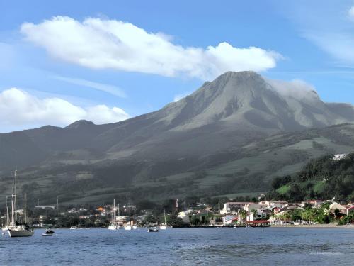 a mountain with a town and boats in the water at Maison de charme à Saint-Pierre avec vue sur mer et montagne in Saint-Pierre