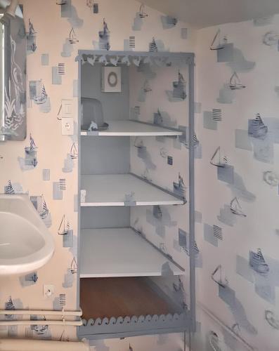 La salle de bains est pourvue d'un lavabo et d'une étagère blanche. dans l'établissement Maison charmante à Mouterre-Silly avec jardin privé, à Mouterre-Silly
