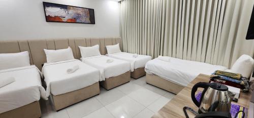 a hotel room with three beds and a table at Orchid Hotel Madinah in Al Madinah