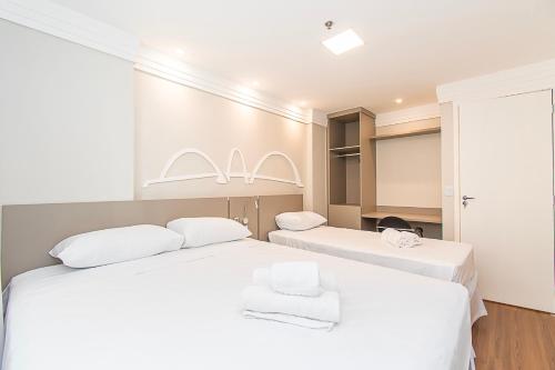 two beds in a room with white sheets at BSB STAY Torre Flats Particulares - Mercure Líder in Brasilia