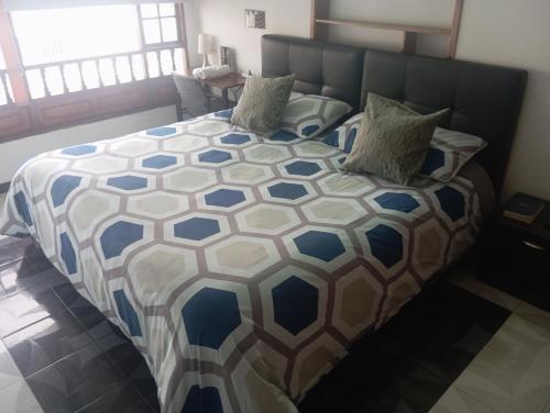 a bedroom with a bed with a blue and white comforter at HOTEL MENDOZA BOUTIQUE - Cerca Aeropuerto El Dorado in Bogotá