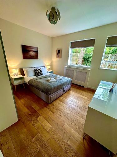 a large bedroom with a bed and two windows at Quiet residential area modern and cozy two bed apartment in Hampstead in London