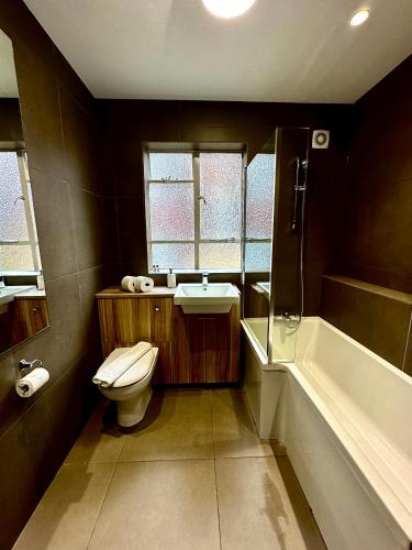 a bathroom with a toilet and a sink and a tub at Quiet residential area modern and cozy two bed apartment in Hampstead in London