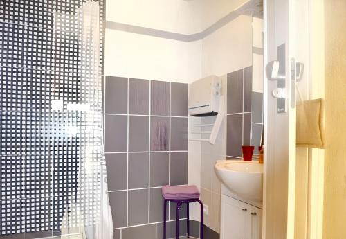 une salle de bain avec un lavabo et une douche avec un tabouret violet dans l'établissement Maison charmante à Cardet avec piscine partagée, à Cardet