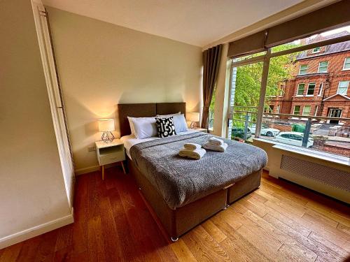 a bedroom with a bed and a large window at Quiet residential area modern and cozy two bed apartment in Hampstead in London