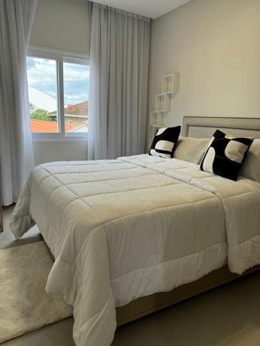 a bedroom with a large white bed with a window at Condomínio Smv in Barra Velha