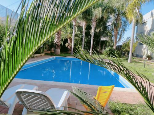 a swimming pool in a yard with chairs and palm trees at Villa Gabry in Floridia