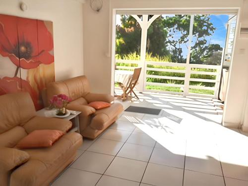 a living room with couches and a sliding glass door at Appartement charmant Deshaies vue mer in Deshaies