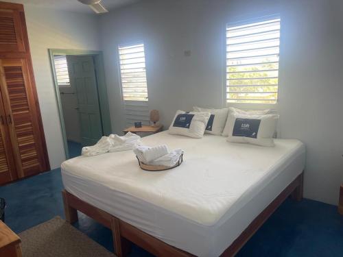 a large white bed in a room with two windows at The Bakers Villa Old Wharf Ltd in Treasure Beach