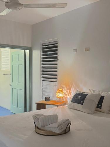a white bedroom with a bed with a lamp on a table at The Bakers Villa Old Wharf Ltd in Treasure Beach