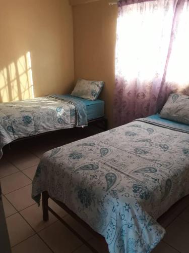a bedroom with two beds and a window with curtains at OrbanLife Lite Keetmanshoop in Keetmanshoop