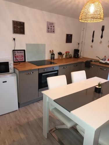 a kitchen with a table and a white table and chairs at Le gîte du puits in Brigueuil
