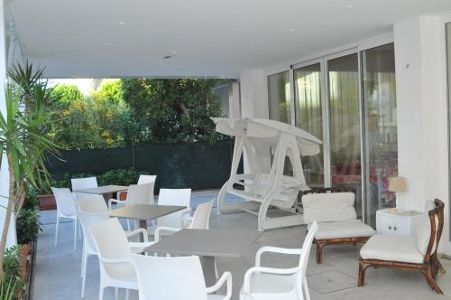 a patio with white tables and white chairs at Pensione Elena in Misano Adriatico
