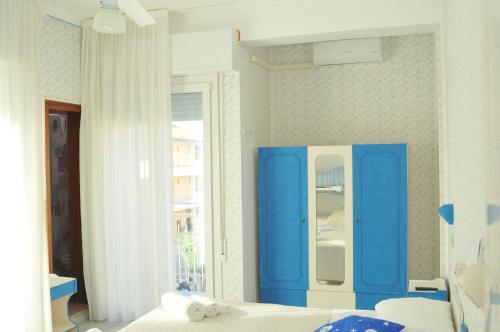 a bedroom with a blue cabinet next to a bed at Pensione Elena in Misano Adriatico