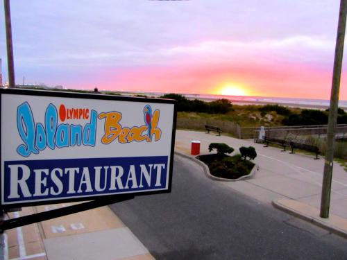 a sign for a beach resort with the sunset in the background at Olympic Island Beach Resort in Wildwood Crest
