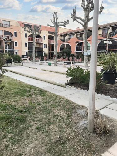 a sidewalk in front of a building with palm trees at Appartement cosy à Canet-en-Roussillon de 25 m² avec terrasse in Canet-en-Roussillon